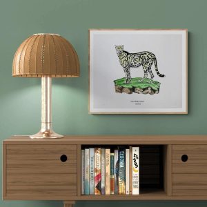 framed hand drawn picture of a king cheetah on a green wall above a wooden cabinet with a lamp to the left
